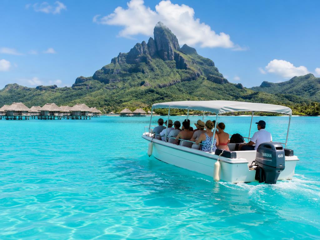 Excursion boat carrying travelers across Bora Bora's turquoise lagoon beneath Mount Otemanu