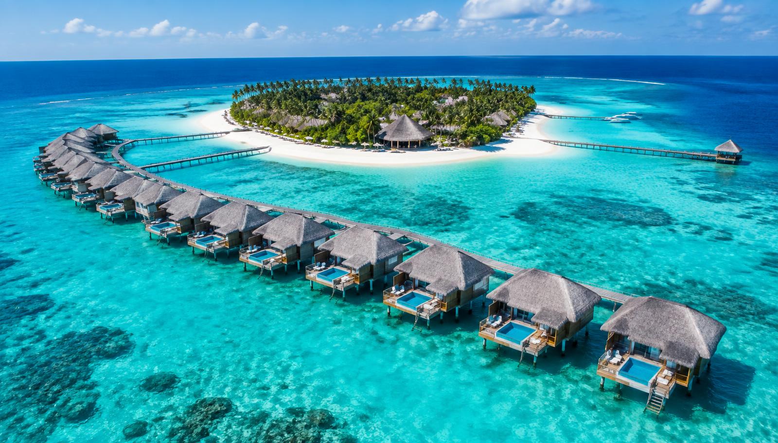 Overwater villas curving over a turquoise lagoon beside a private resort island in the Maldives