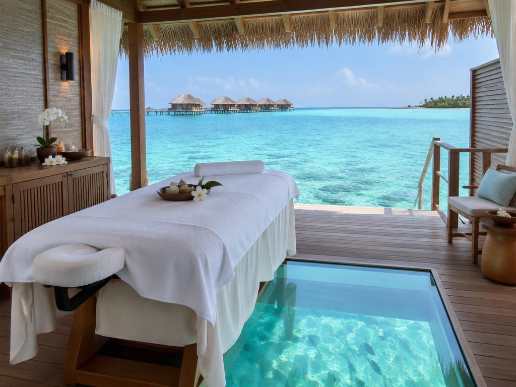Overwater spa treatment room with a glass floor panel overlooking the lagoon in the Maldives