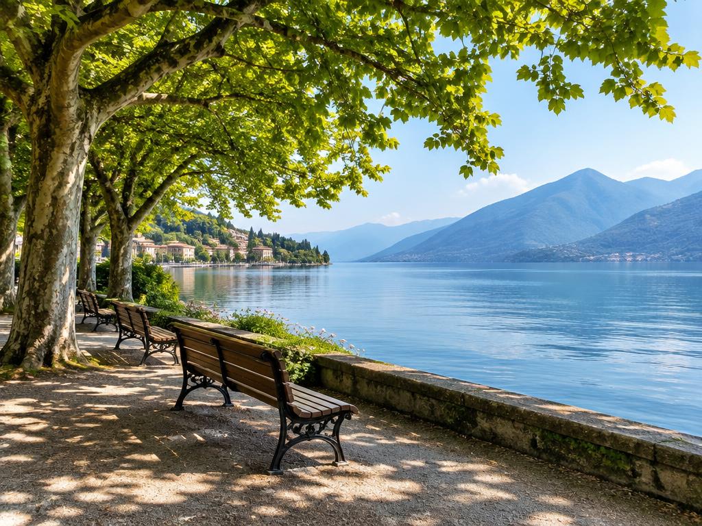 Shaded lakeside promenade with benches and mountains across calm water